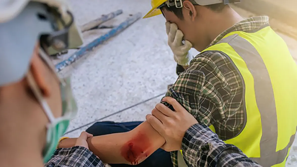 Injured construction worker receiving help at a job site