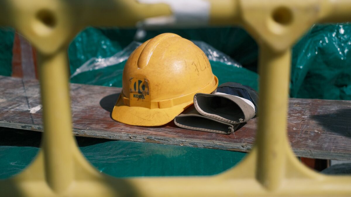 A hard hat and work gloves on a plank at a construction site