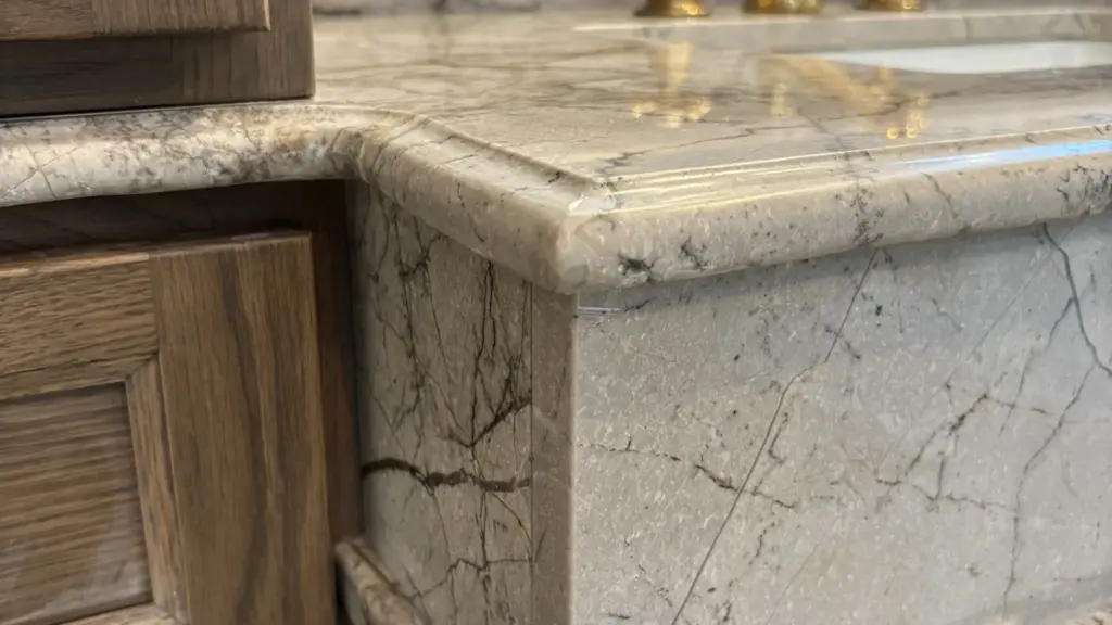 Edge of a stone bathroom vanity top on a wooden cabinet