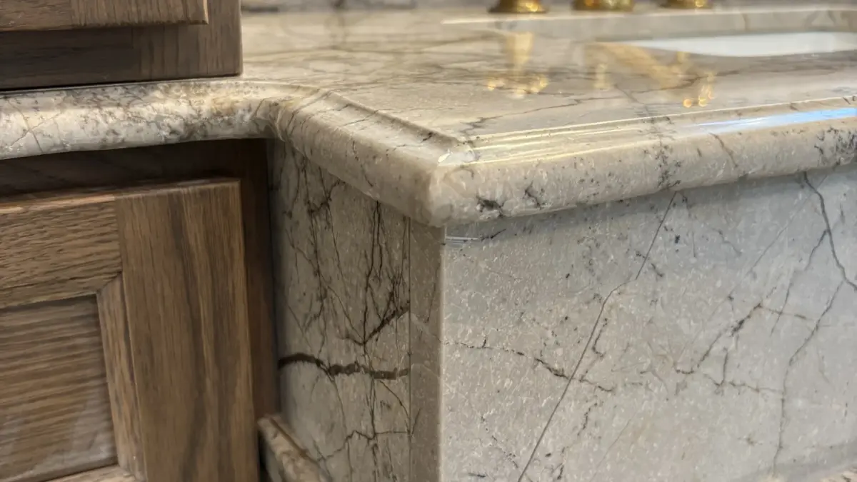 Edge of a stone bathroom vanity top on a wooden cabinet