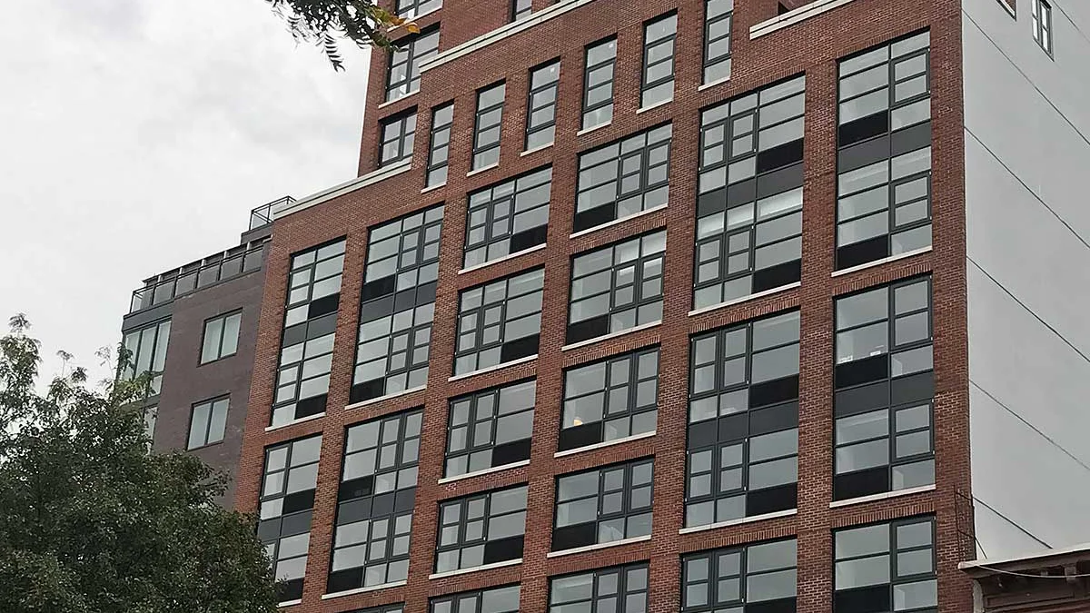Brick multifamily building in New York with rows of new windows